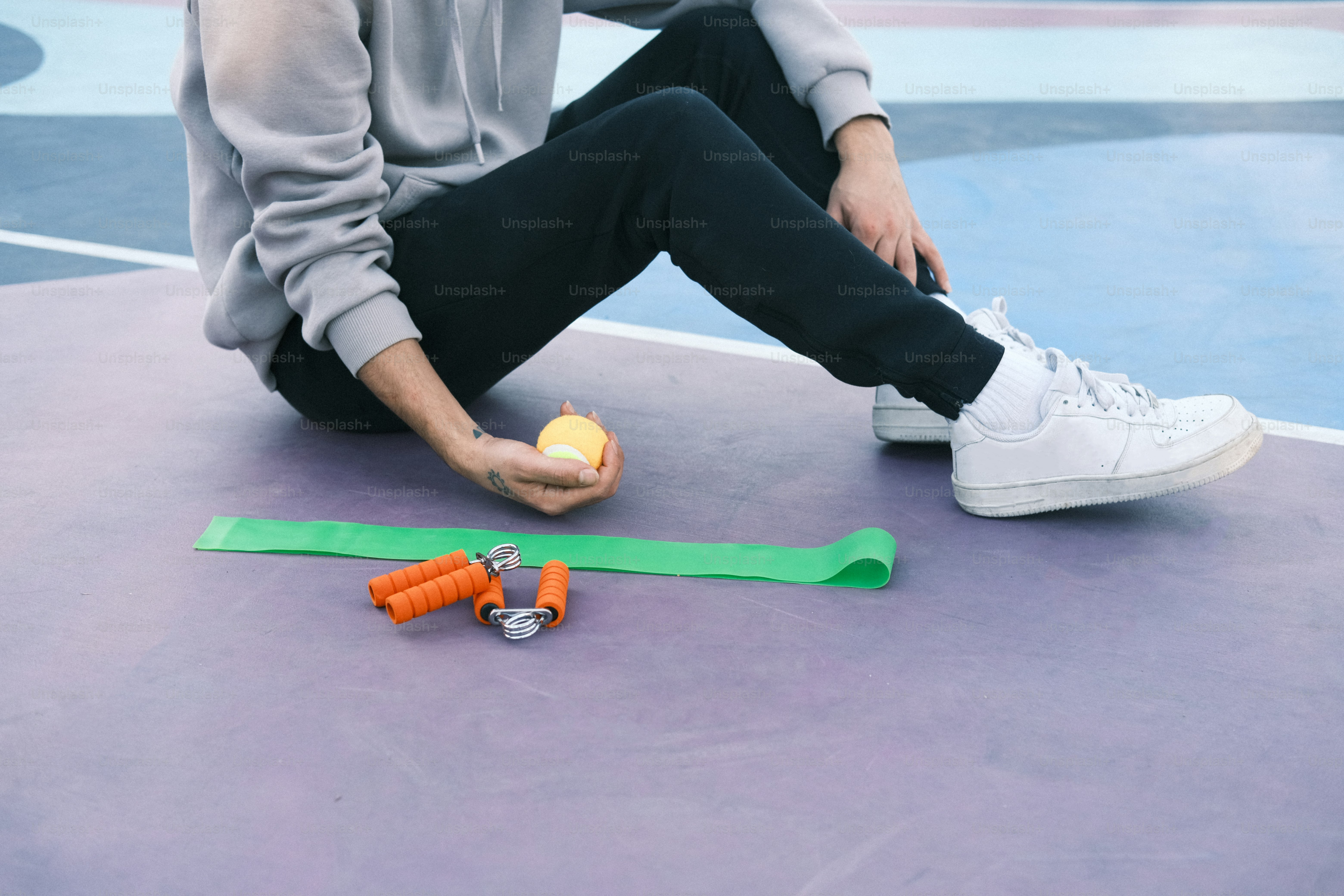 a person sitting on the ground with a tennis ball and carrots